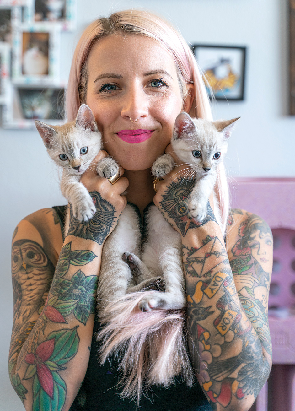 Photo of Hannah holding two little gray tabby kittens while smiling